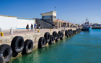 Ferry docked near Robben Island with tourists walking along the pier.