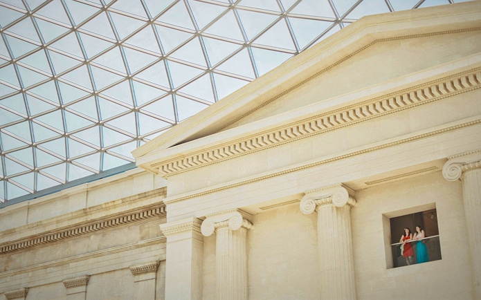 British Museum interior with visitors on balcony under glass roof, London.