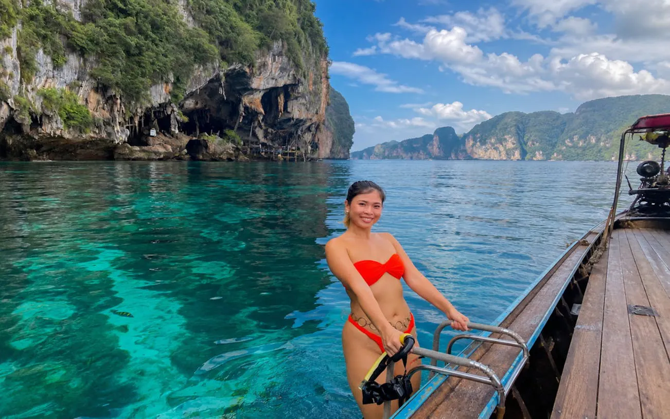 Woman on a speedboat near Phi Phi Islands, clear water, limestone cliffs in background.