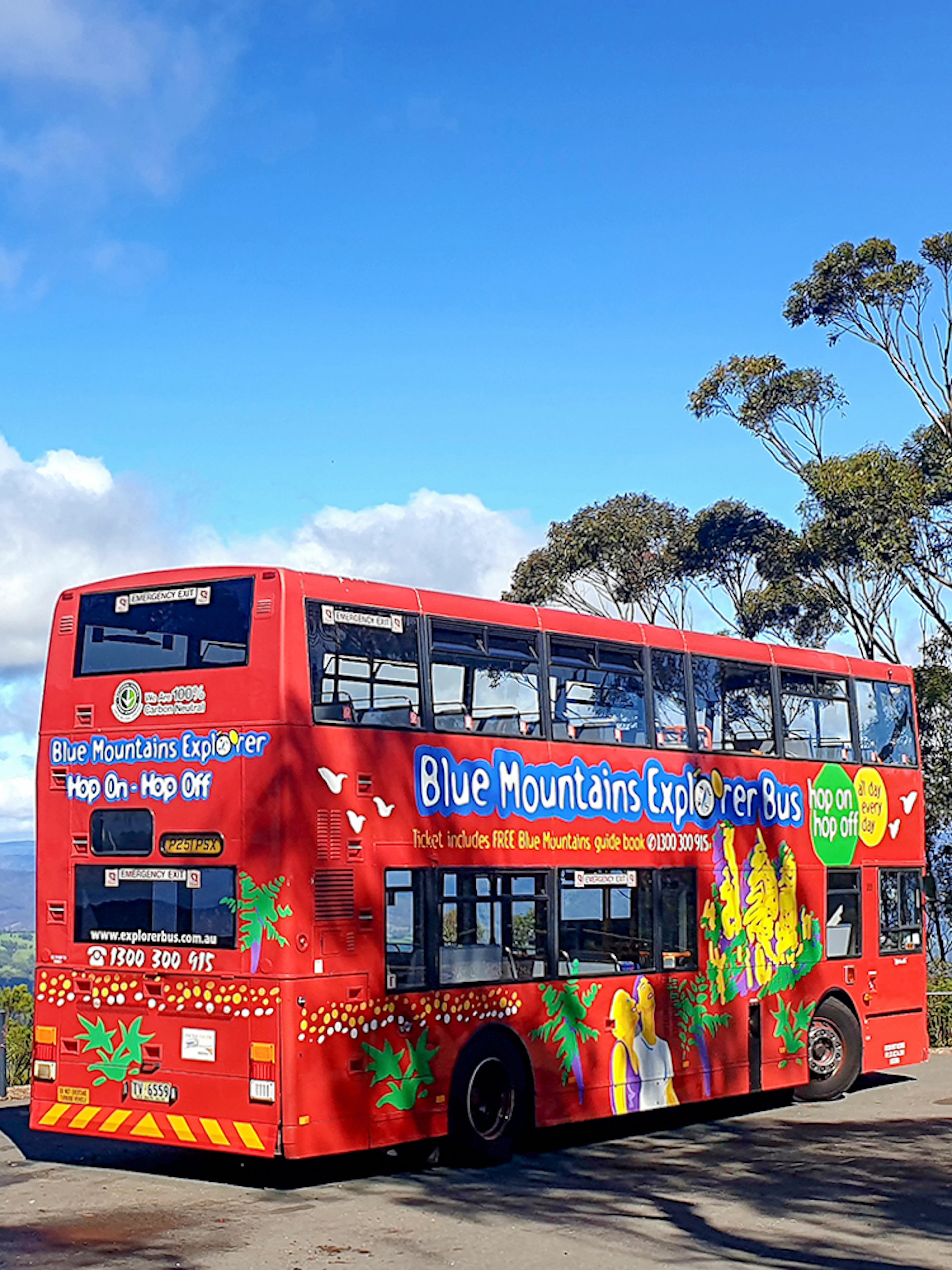 Red double-decker bus on Blue Mountains Hop-On-Hop-Off Tour with scenic view.