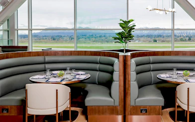 Seating area at Plaza Premium First lounge, Vancouver International Airport, with runway view.