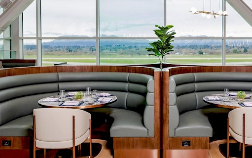 Seating area at Plaza Premium First lounge, Vancouver International Airport, with runway view.