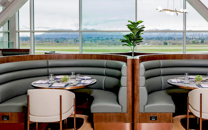 Seating area at Plaza Premium First lounge, Vancouver International Airport, with runway view.