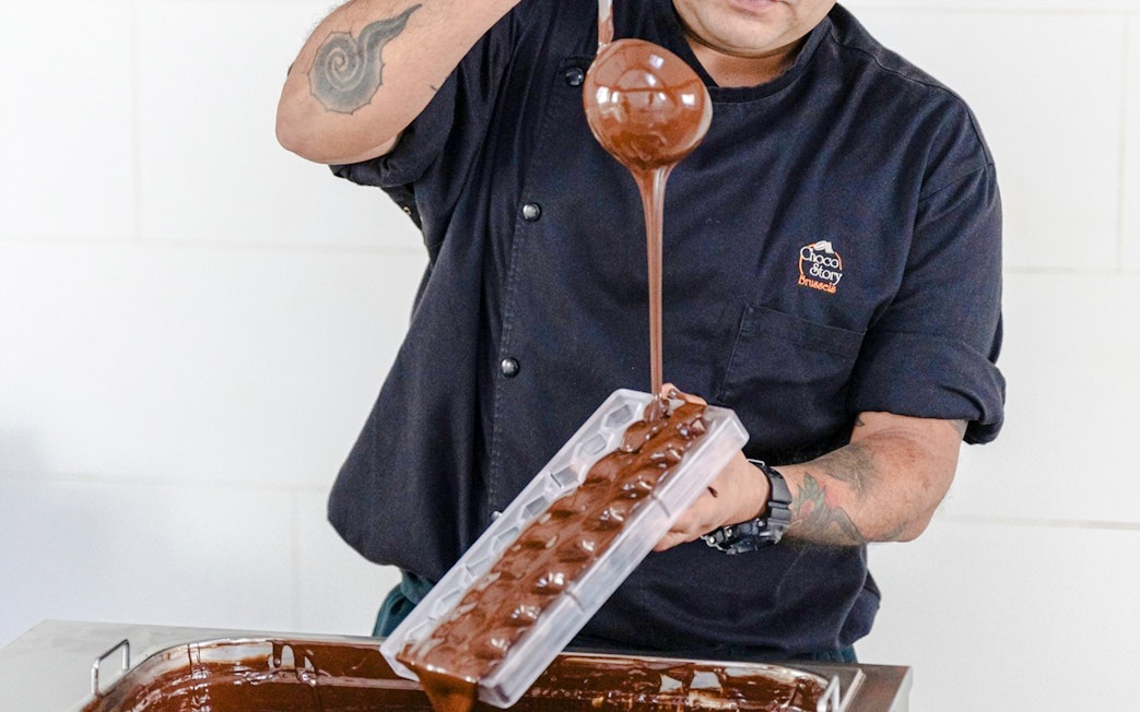 Host pouring chocolate into mold at Choco-Story Brussels Museum.