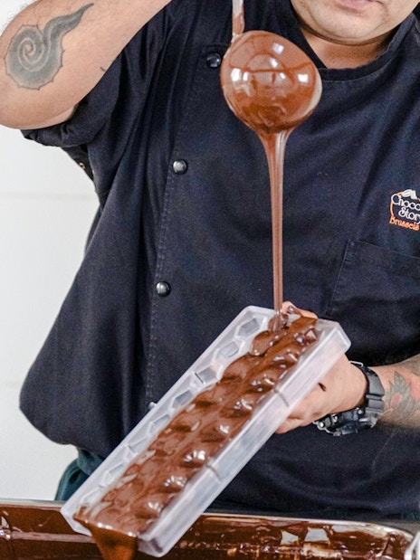 Host pouring chocolate into mold at Choco-Story Brussels Museum.