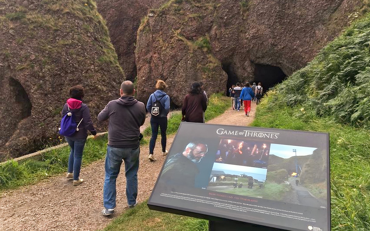 Tourists walking towards a cave on the Game of Thrones locations tour in Belfast.