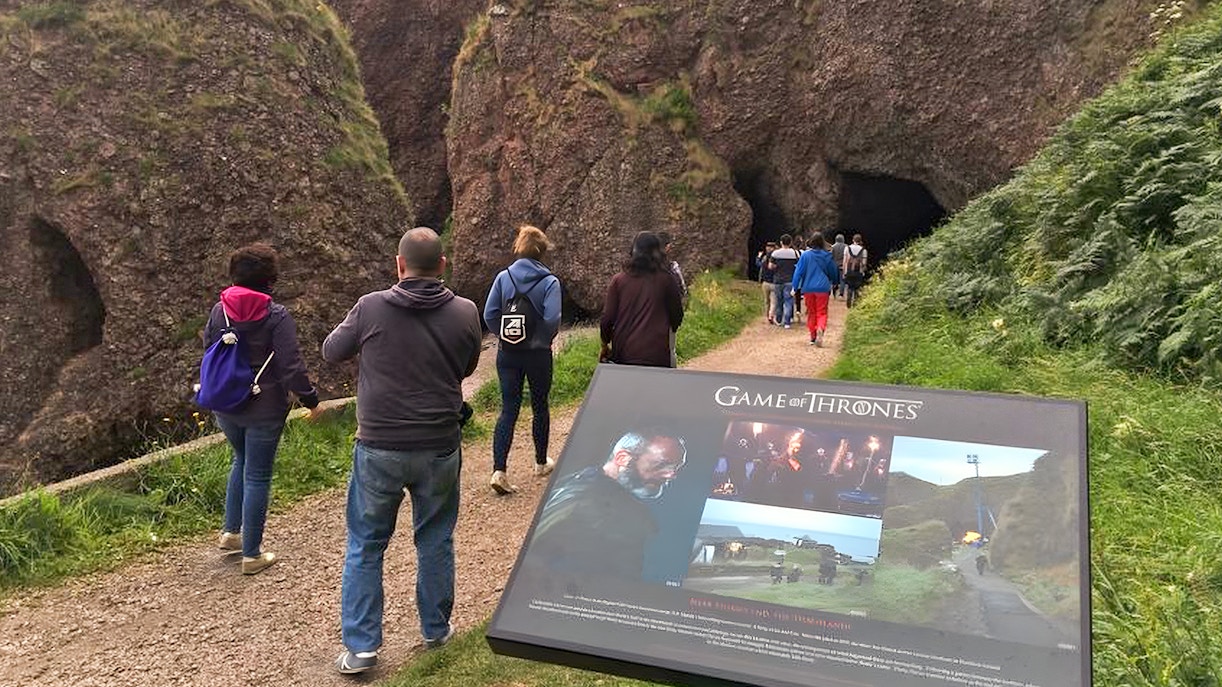 Tourists walking towards a cave on the Game of Thrones locations tour in Belfast.