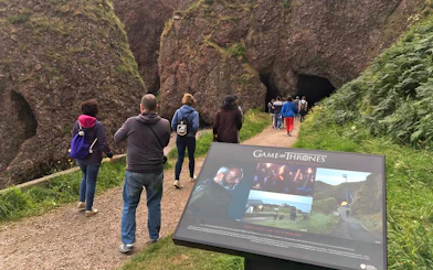 Tourists walking towards a cave on the Game of Thrones locations tour in Belfast.