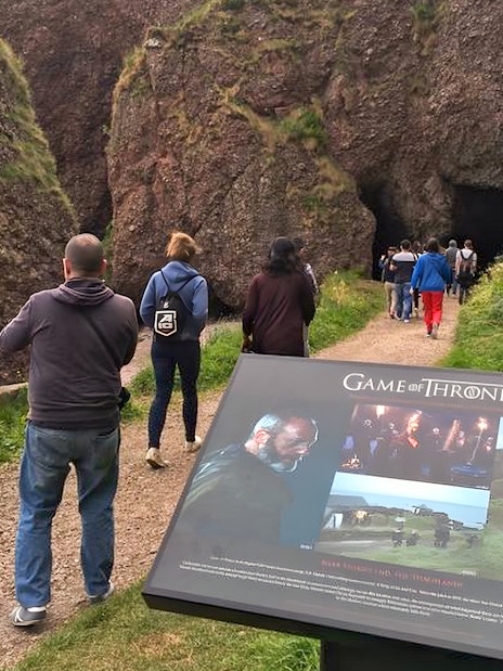 Tourists walking towards a cave on the Game of Thrones locations tour in Belfast.