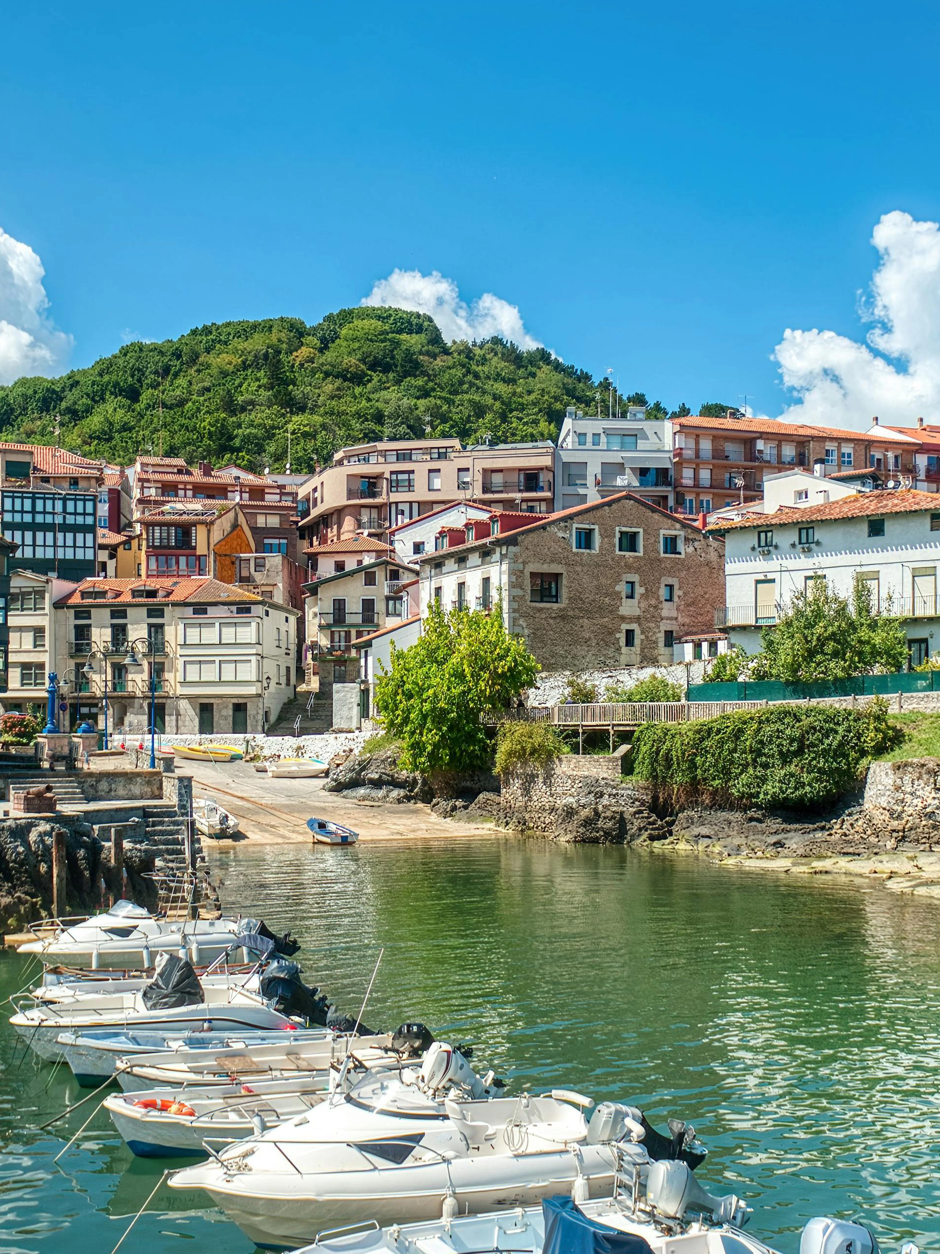 Boats docked at the Mundaca estuary with hillside houses in Vizcaya, Spain.