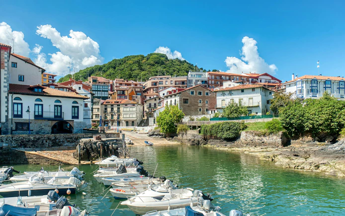 Boats docked at the Mundaca estuary with hillside houses in Vizcaya, Spain.