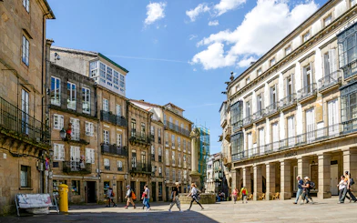 Praza De Cervantes in Santiago de Compostela with traditional buildings and people walking.