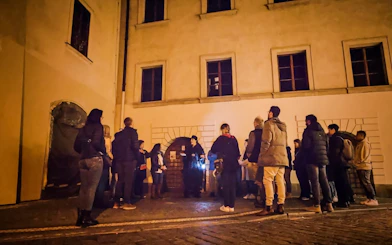 Group listening to guide during Ghosts & Legends tour in Old Town Prague at night.