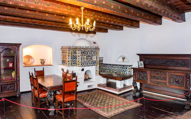 Dining room with ornate wood furniture and tiled stove inside Bran Castle, Romania.