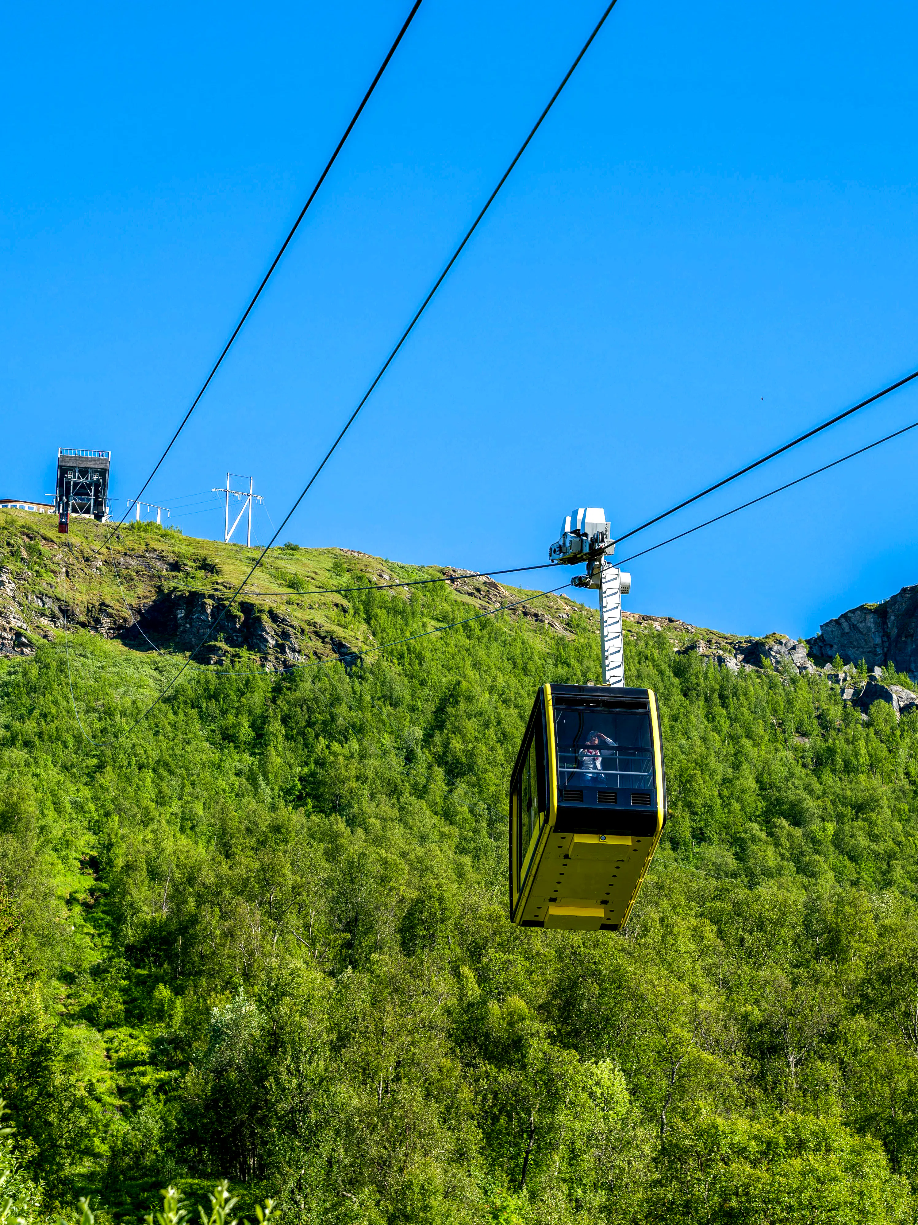 Fjellheisen cable car ascending over green hills in Tromso, Norway.