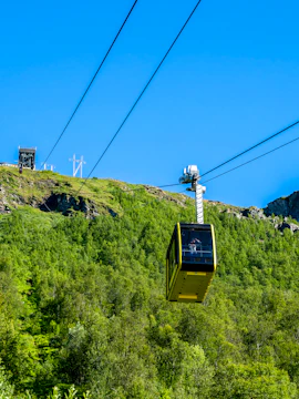 Fjellheisen cable car ascending over green hills in Tromso, Norway.