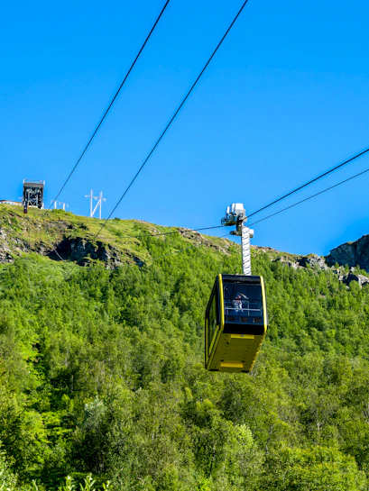 Fjellheisen cable car ascending over green hills in Tromso, Norway.