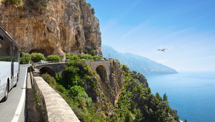 Coastal road on Amalfi Coast with bus and cars heading to Positano, Italy.