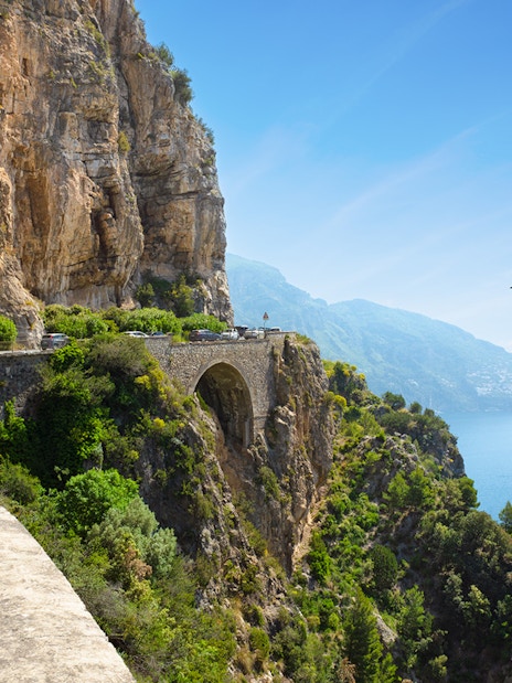 Coastal road on Amalfi Coast with bus and cars heading to Positano, Italy.