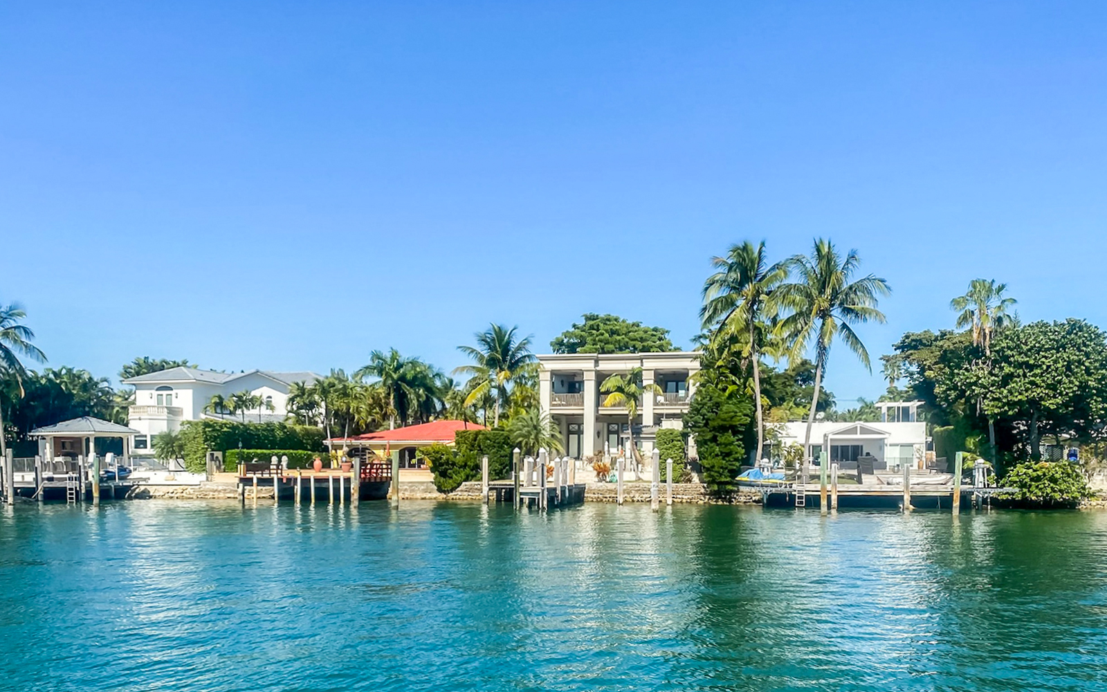 Luxury homes along Miami waterfront with palm trees and private docks.