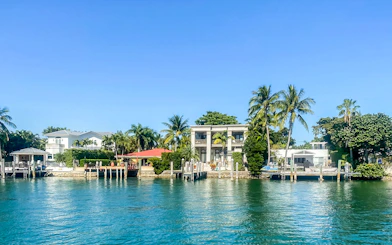 Luxury homes along Miami waterfront with palm trees and private docks.