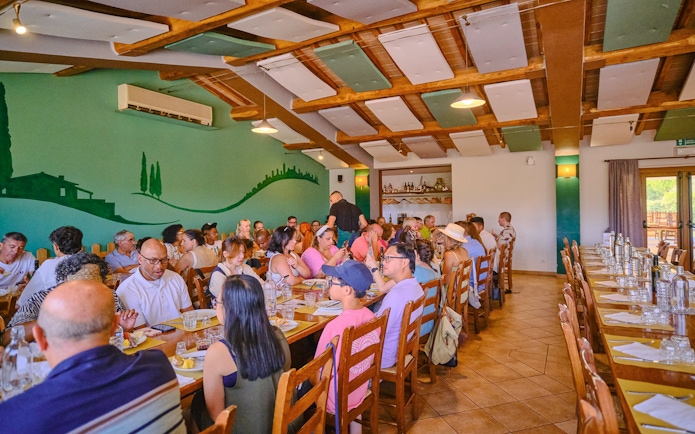 People dining at a long table during Pisa, Siena, and San Gimignano day trip.