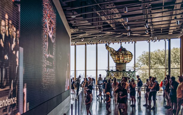 Visitors inside the Statue of Liberty Museum viewing the original torch exhibit.