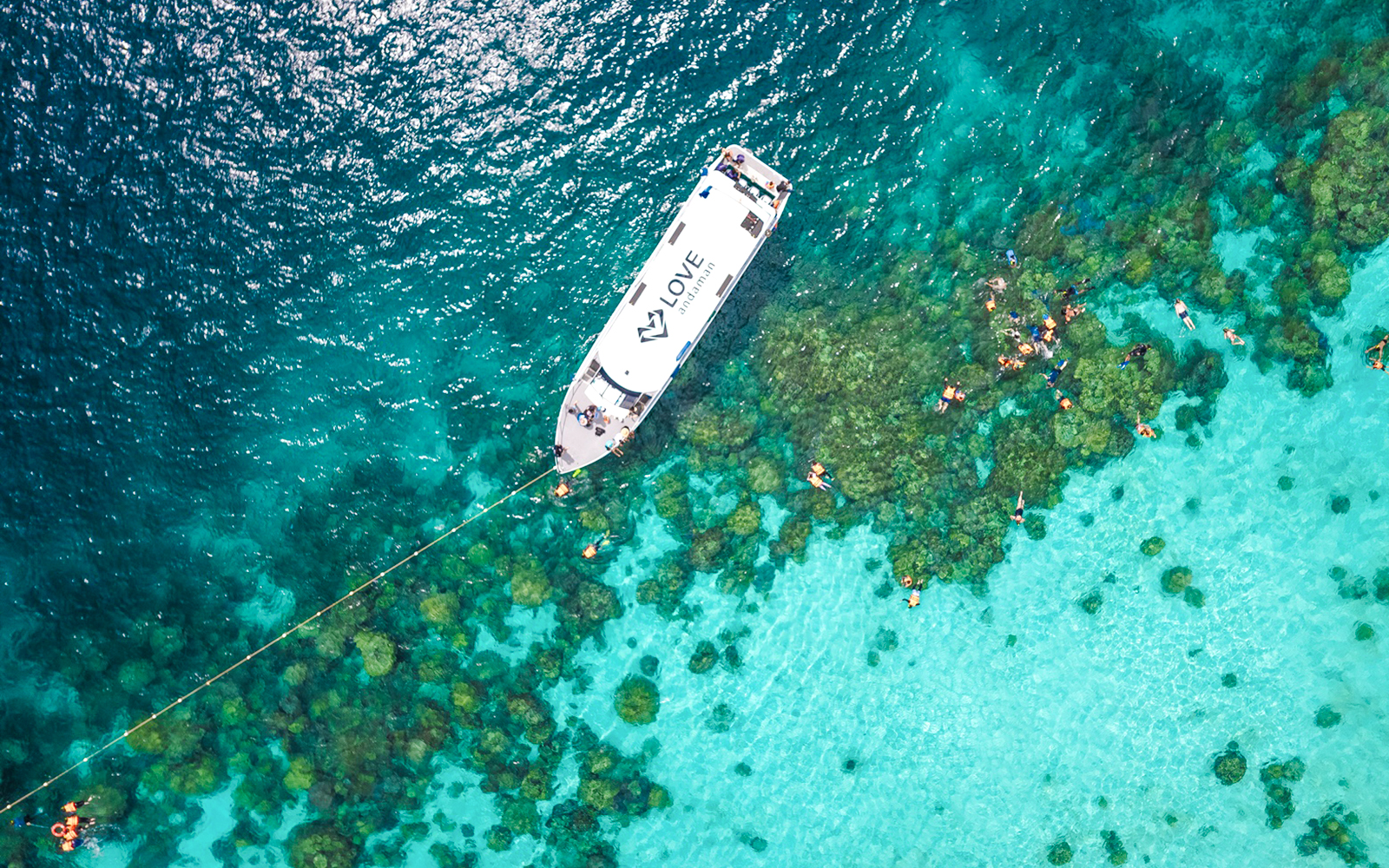 Speedboat near coral reef with snorkelers in Surin Islands, Thailand.