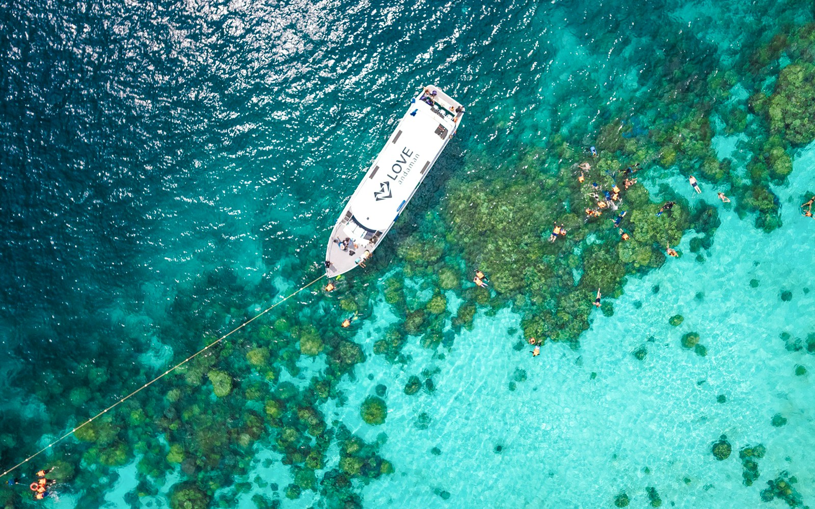 Speedboat near coral reef with snorkelers in Surin Islands, Thailand.