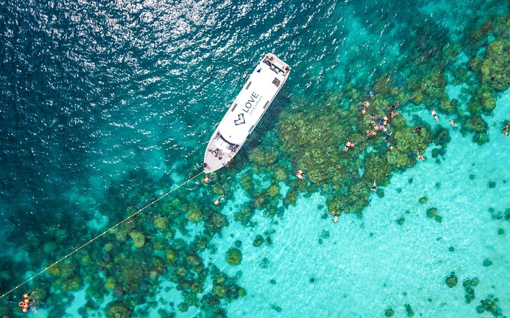 Speedboat near coral reef with snorkelers in Surin Islands, Thailand.
