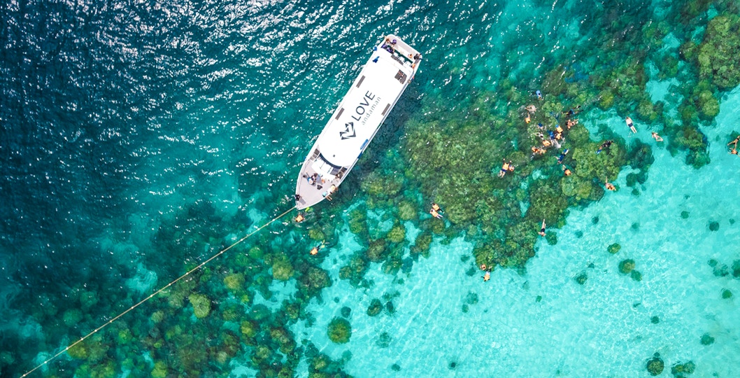 Speedboat near coral reef with snorkelers in Surin Islands, Thailand.