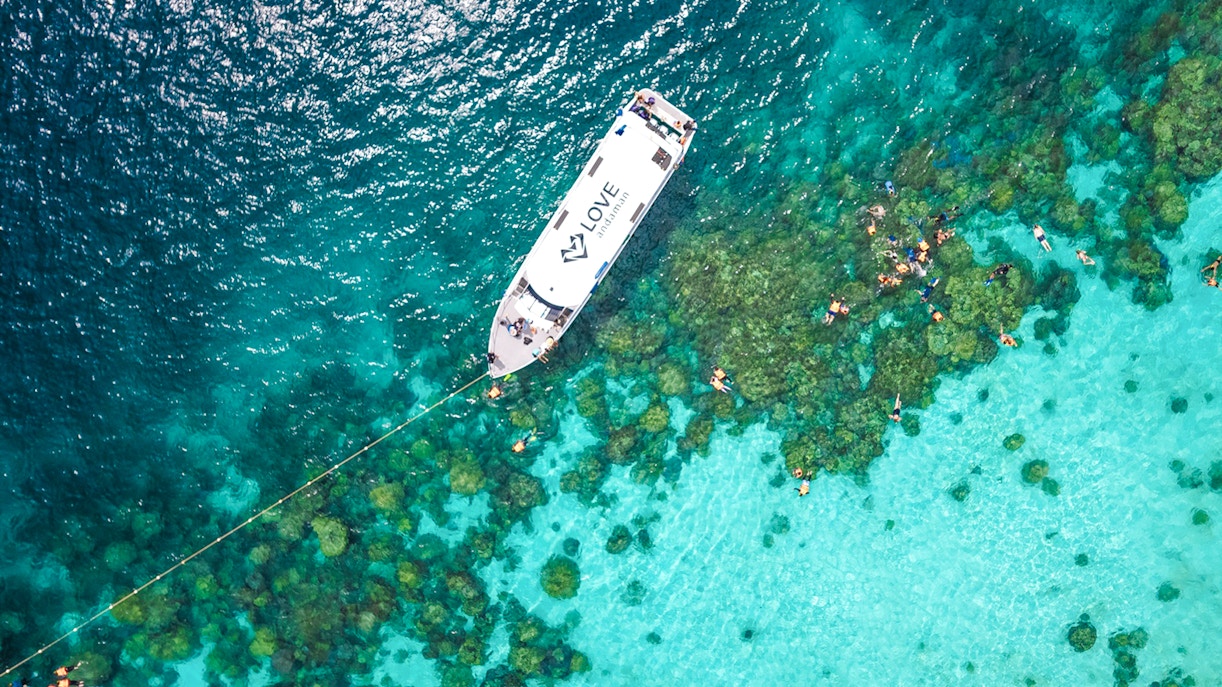 Speedboat near coral reef with snorkelers in Surin Islands, Thailand.