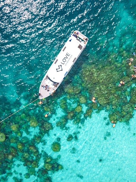 Speedboat near coral reef with snorkelers in Surin Islands, Thailand.