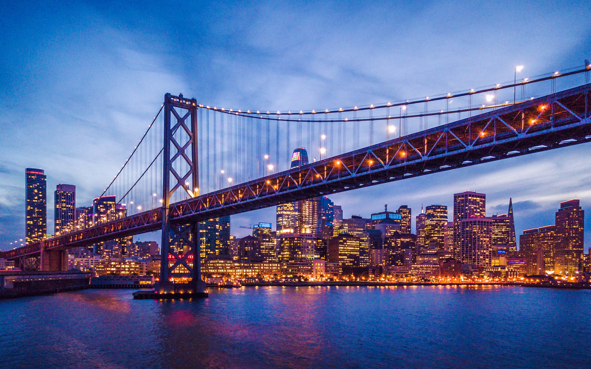 San Francisco skyline and Bay Bridge illuminated at night.