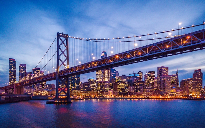 San Francisco skyline and Bay Bridge illuminated at night.