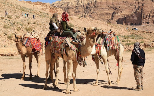 Camels with riders in colorful blankets at a desert site near Hurghada, Egypt.
