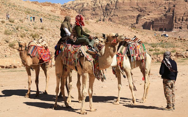 Camels with riders in colorful blankets at a desert site near Hurghada, Egypt.