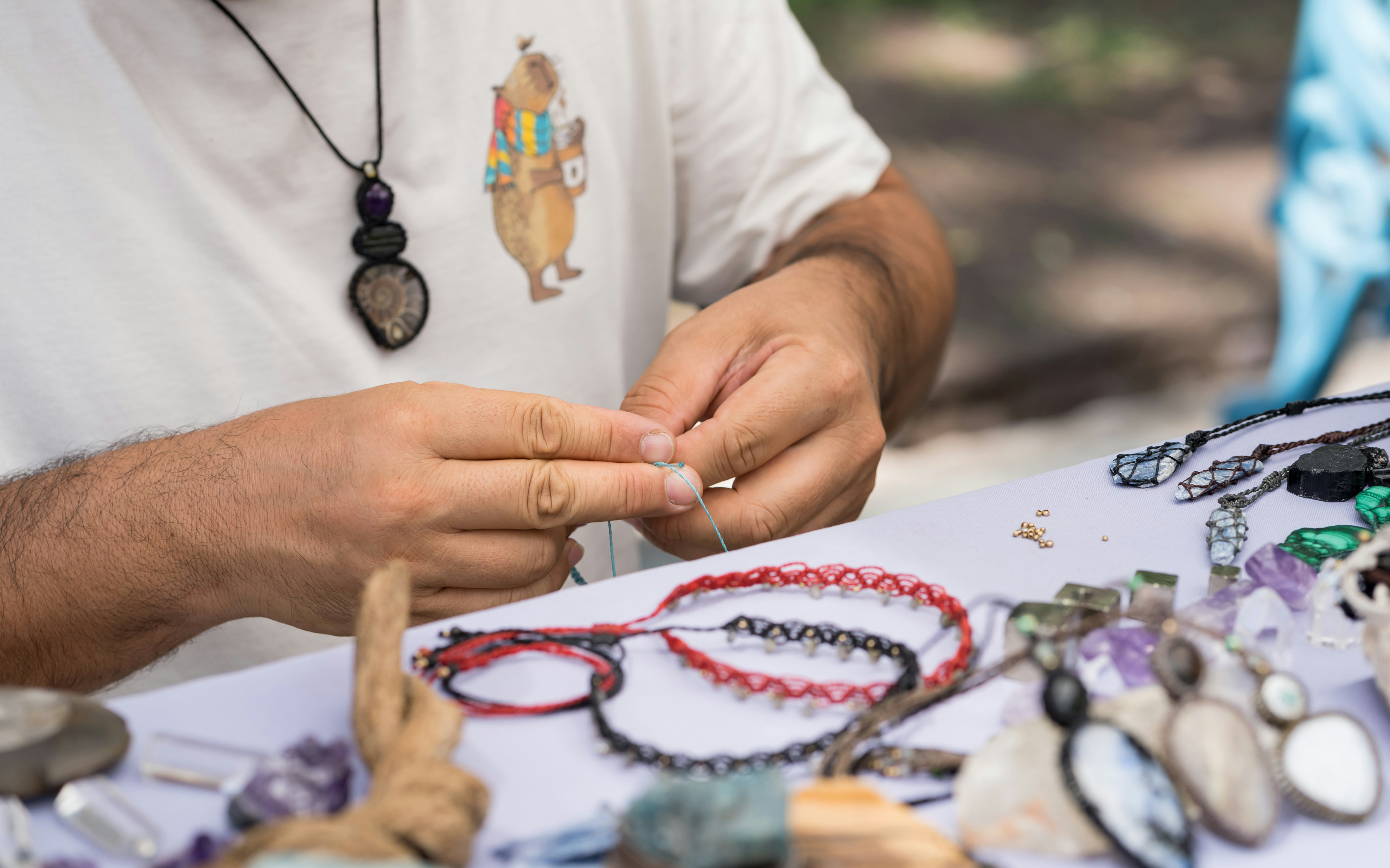 Crafting a tulip necklace with beads and thread at a jewelry-making workshop.
