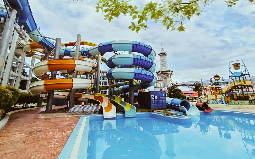 Colorful water slides at Splash Out Langkawi Water Theme Park, Malaysia, with a pool and tower in view.