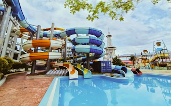 Colorful water slides at Splash Out Langkawi Water Theme Park, Malaysia, with a pool and tower in view.