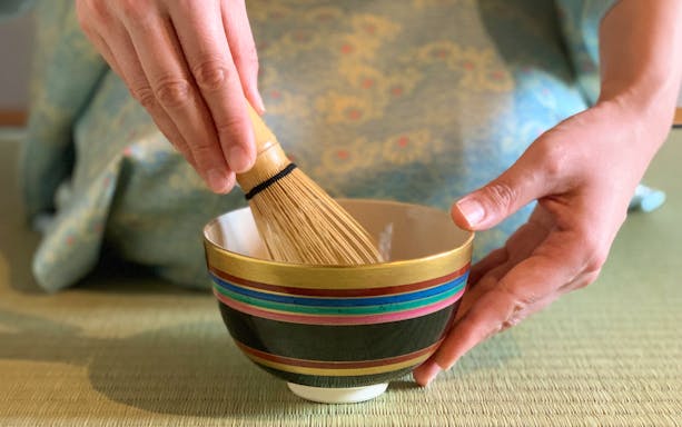 Tea ceremony preparation with bamboo whisk in Kyoto teahouse.