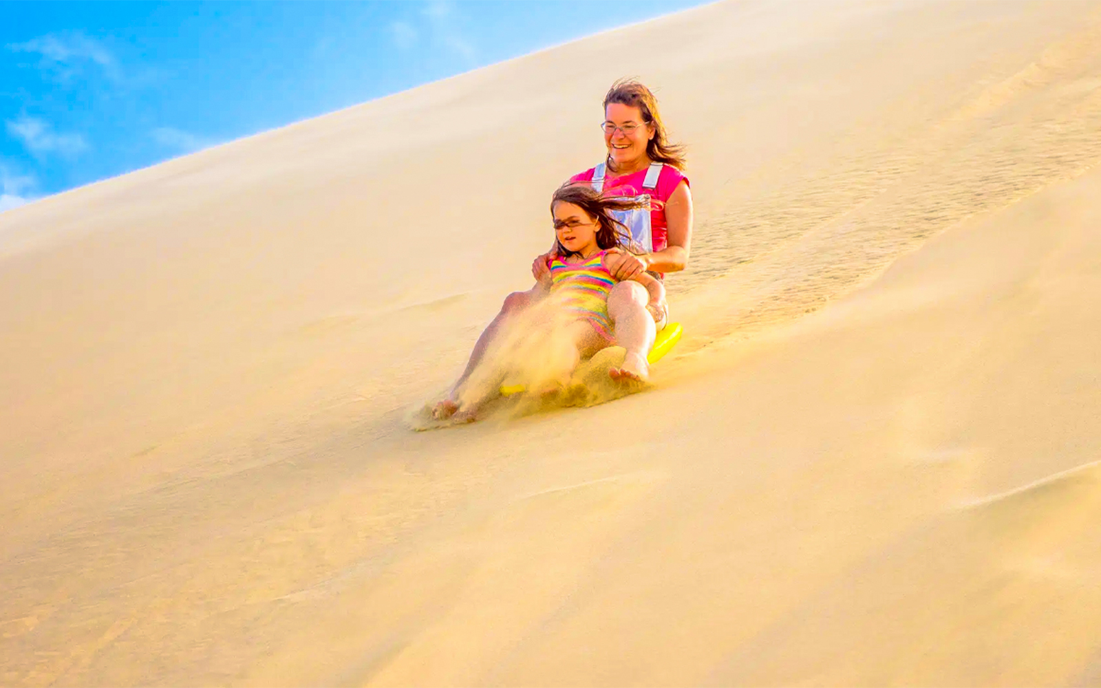 Sandboarding down a dune at Dubai desert safari.
