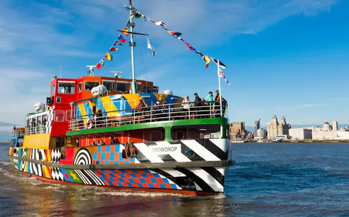 Colorful ferry on Mersey River with Liverpool skyline in background.