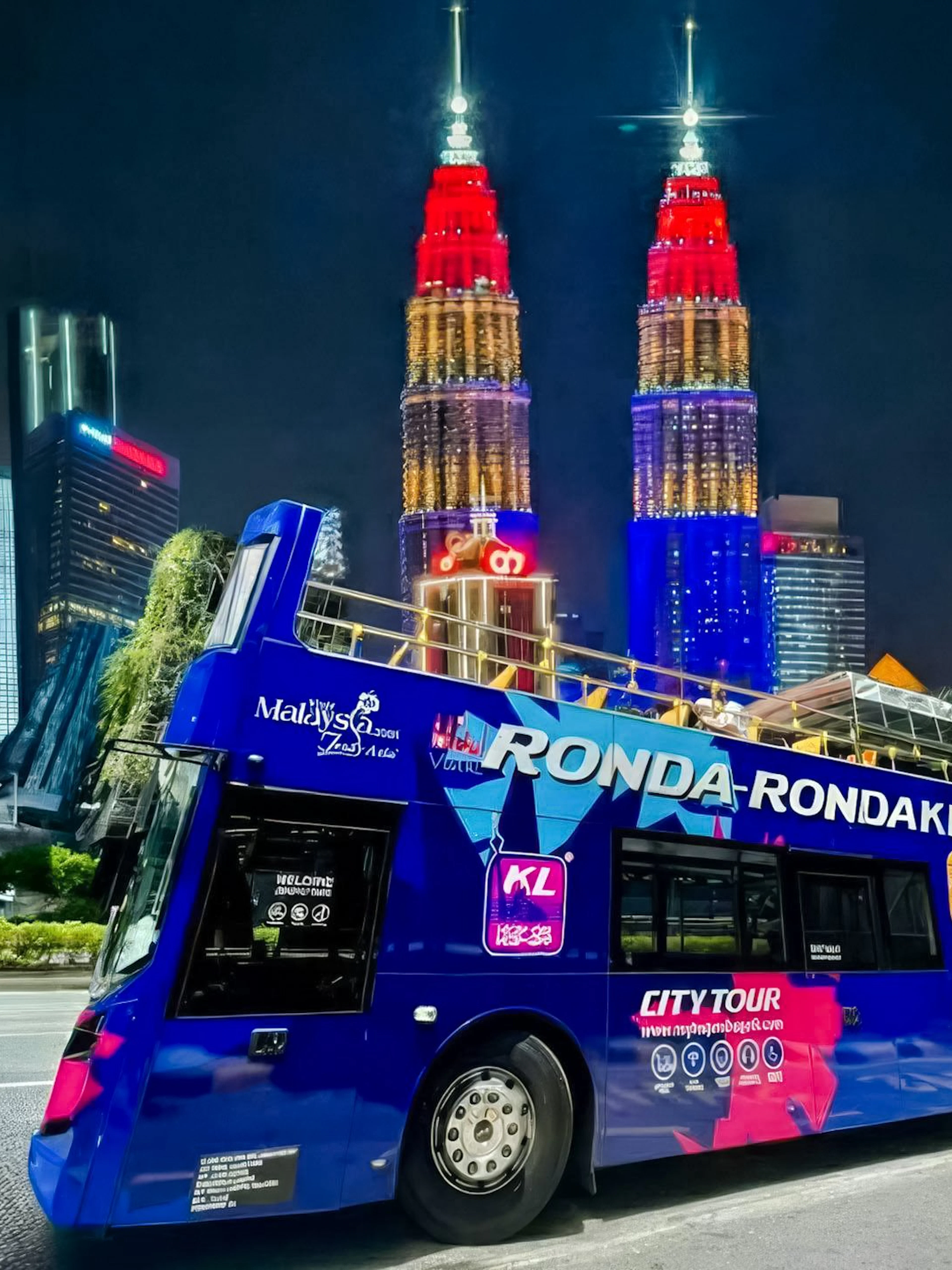 Open-top bus in Kuala Lumpur with Petronas Towers illuminated at night.