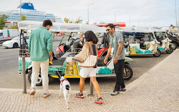 Tourist boarding eco tuk-tuk with pet in Lisbon.