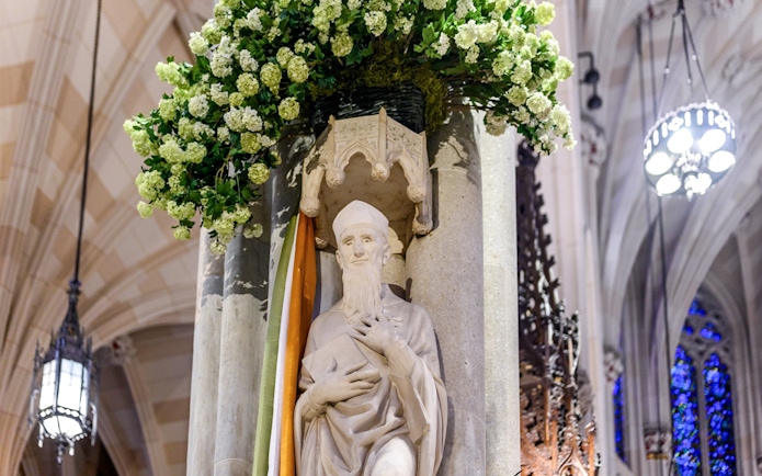 Statue inside St. Patrick's Cathedral with floral decoration, part of the official tour.