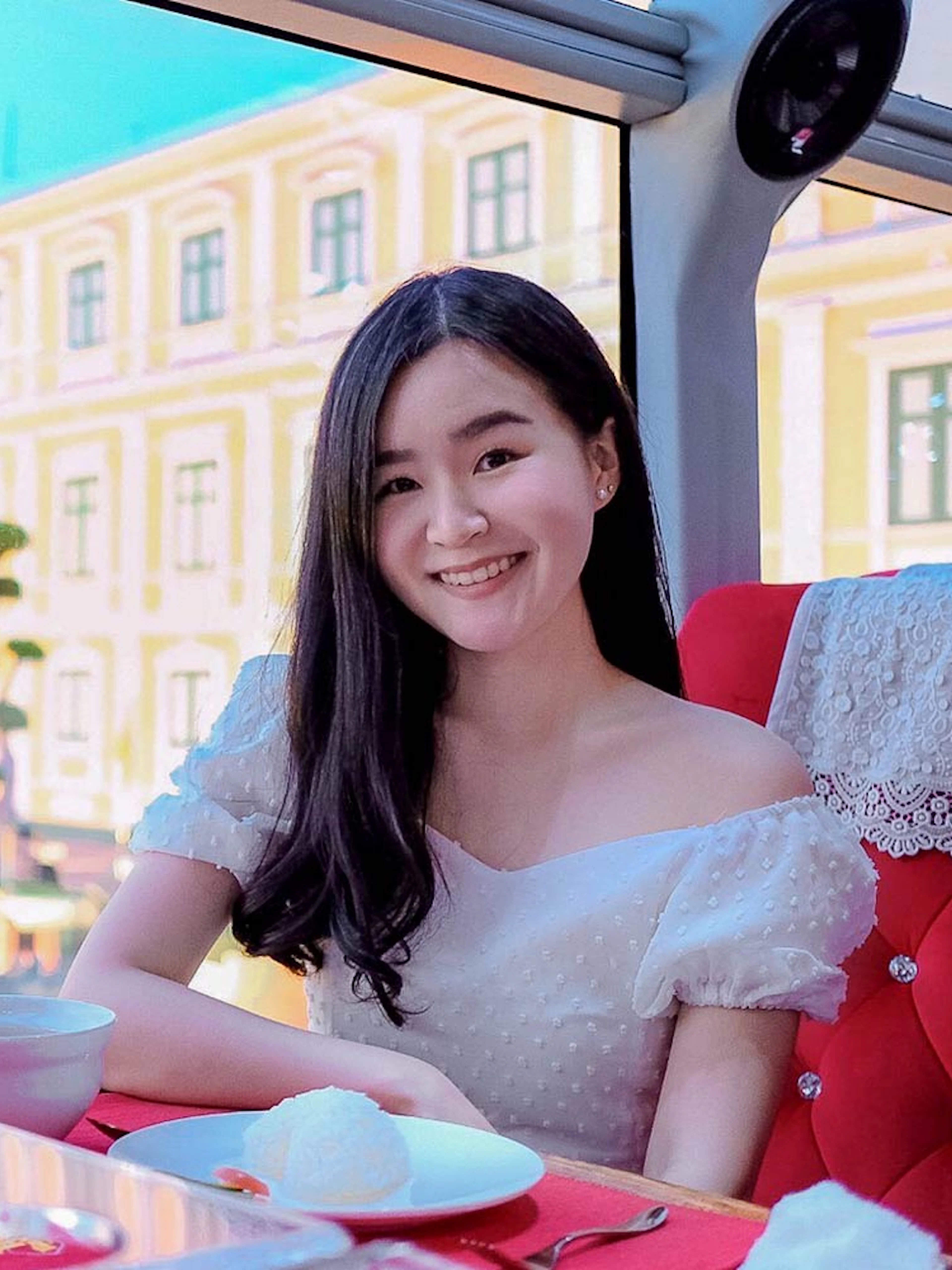 Woman enjoying meal on Thai bus food tour with historic building view.