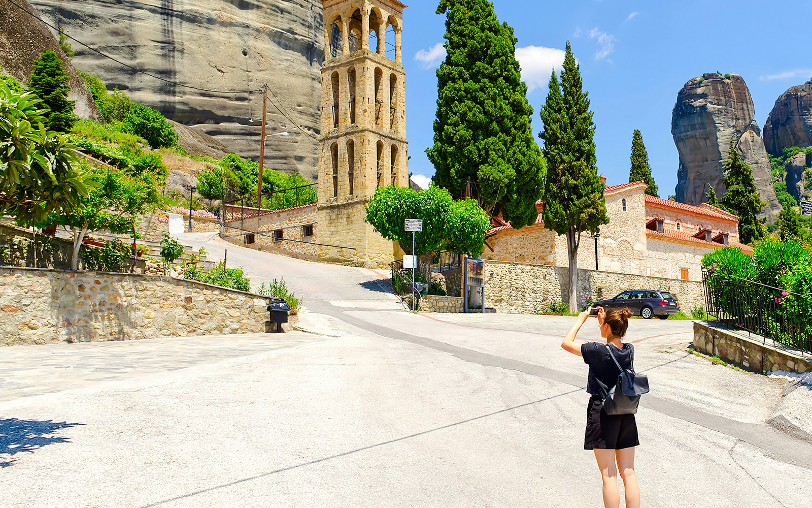 Tourist photographing Byzantine Church bell tower in Meteora, Greece.