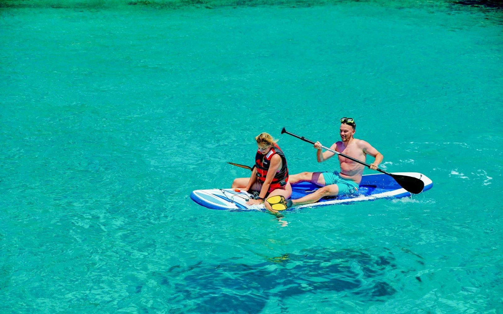 Guests paddleboarding on clear waters during Ierapetra to Chrissi Island catamaran cruise.