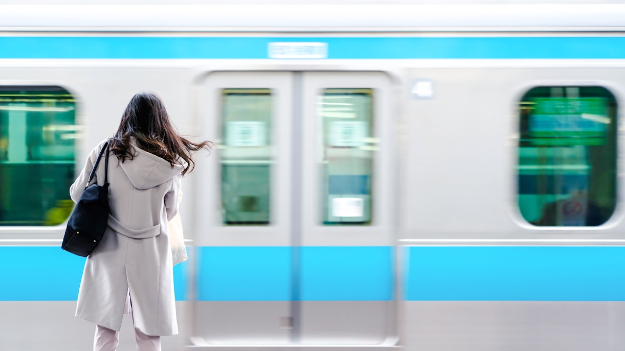 Woman standing on platform as train passes in Japan.